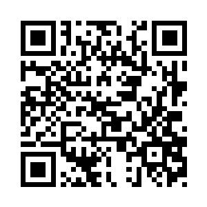 一个面露笑容的妇人拄着锄头站在田间二维码生成